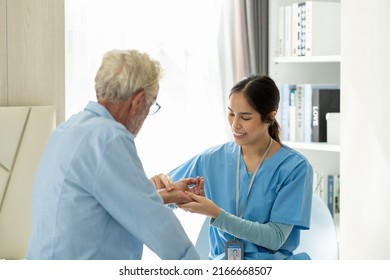 Caring Asian Nurse Taking Care Of Old Man Patient At Hospital. Friendly Female Doctor Caring Elderly Man Patient. Happy Woman With Her Caregiver At Nursing Home.