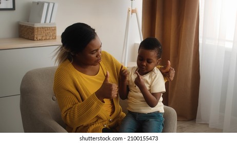 Caring Black Mother Teaching Her Little Son Counting On Fingers At Home, Loving Mom Playing With Male Child, Showing Different Hand Gestures To Preschooler Kid While Sitting Together In Chair