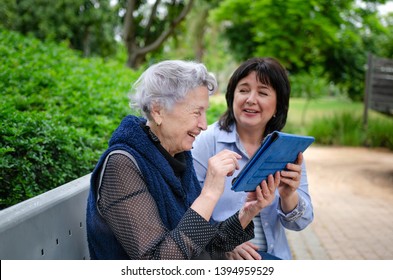 Caring daughter teaching her elderly mother how to use a tablet in social networks - Powered by Shutterstock