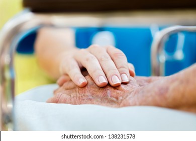 Caring Doctor Or Nurse Holding Elderly Lady's Hands In Wheelchair.