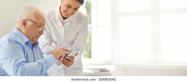 Caring Doctor Teaching Senior Patient To Use Healthcare App On Mobile Device That Enables To Set Medicine Reminders, Track Health Indicators, Monitor Weight, Blood Glucose Level, Heart And Pulse Rates