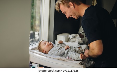 Caring father changing diaper of his baby. Man on paternity leave taking care of his baby. - Powered by Shutterstock