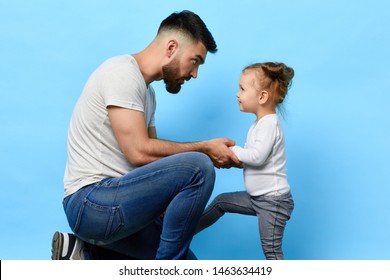 Caring Father And Little Obedient Daughter Who Listens To The Instruction Of Parent On Blue Isolated Background. Daddy Making An Observation To Kid. Dad Asking Daughter To Behave Well