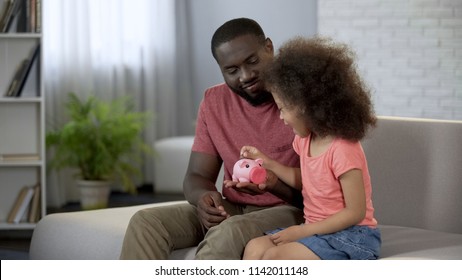 Caring Father Teaching Child To Save Money, Girl Putting Coins Into Piggy Bank