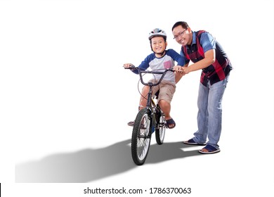 Caring Father Teaching His Boy To Ride Bike For The First Time With Happy Expression In The Studio. Isolated On White Background