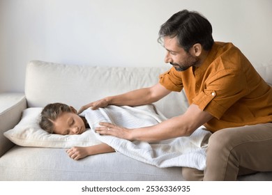 Caring father tucking up sweet little daughter sleeping on at daytime, stroking girl under soft plaid, calming sleepy child. Peaceful asleep kid lying on comfortable couch near loving Latin dad - Powered by Shutterstock