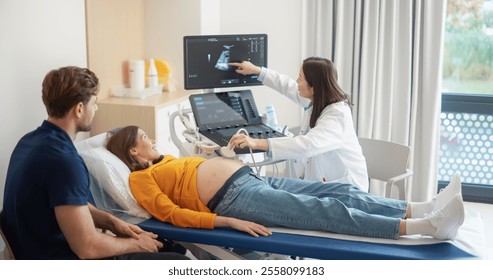 Caring Female Hospital Obstetrician Conducting an Ultrasound Exam for a Pregnant Woman. Young Couple Watching the Screen while Asian Doctor Describes the Baby’s Growth to Expectant Mother - Powered by Shutterstock