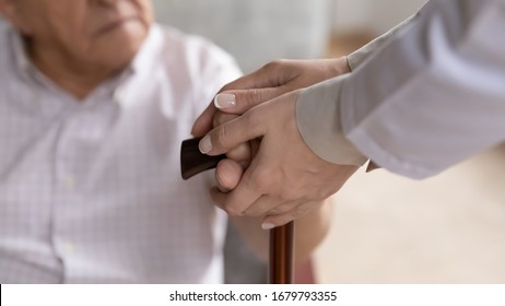 Caring Female Nurse Hands Holding Old Man Patient Arms Touch Walking Stick Close Up Image. Provide Help To Older Generation Person, Psychological Physical Support, Physiotherapy, Nursing Home Concept