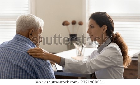 Caring female nurse touch support elderly male patient hear bad news results at hospital consultation. Woman doctor comfort caress old man client at meeting. Geriatrics medicine, healthcare concept.