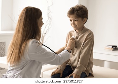 Caring female pediatrician in white coat hold stethoscope listen to little patient heartbeat, examining lungs and heart. Kid get consultation from medical worker. Health services, checkup, pediatry - Powered by Shutterstock