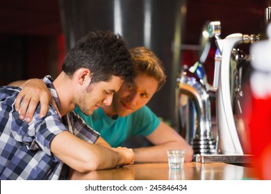 Caring friend comforting upset man at the bar - Powered by Shutterstock