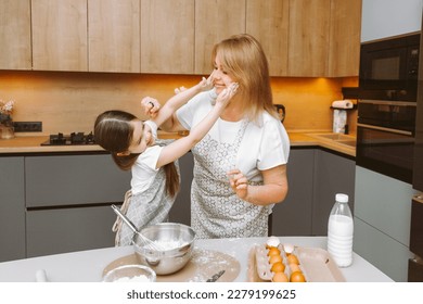Caring grandmother and little granddaughter are having fun baking cookies together in the home kitchen. A loving elderly grandmother and granddaughter prepare a delicious sweet cake. - Shutterstock ID 2279199625