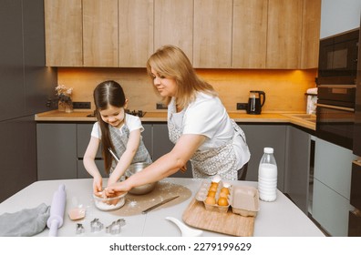 Caring grandmother and little granddaughter are having fun baking cookies together in the home kitchen. A loving elderly grandmother and granddaughter prepare a delicious sweet cake. - Shutterstock ID 2279199629