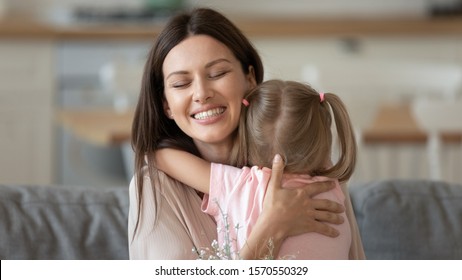 Caring Happy Foster Care Parent Young Adult Attractive Single Mother Embracing Cute Adopted Little Child Daughter Feeling Love And Tenderness Concept Hugging Small Kid Girl Bonding Cuddling At Home