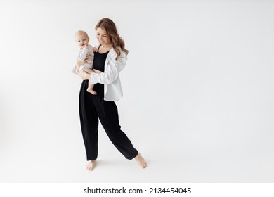 Caring happy mother gently hugging and kissing her beautiful little daughter, enjoy the moment. Lovely young woman with cute baby girl posing in studio, spend time together, tenderness concept - Powered by Shutterstock