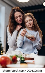 Caring, Hugging Mother Next To Her Daughter Eating Granola