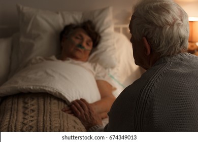 Caring husband holding his sick wife's hand - Powered by Shutterstock