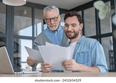 Caring loving adult son helping his old senior elderly father paying bills, counting money, doing paperwork at home together. Aid to elderly generation. Happy father`s day! - Powered by Shutterstock