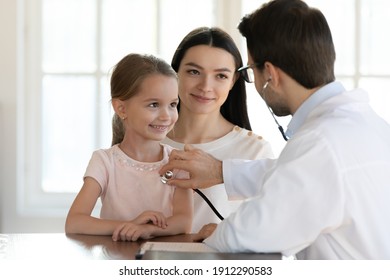 Caring Male Cardiologist Hold Stethoscope Listen To Small Girl Kid Patient At Heart At Consultation With Mom. Man GP Doctor Examine Little Child Client At Meeting In Hospital. Healthcare Concept.