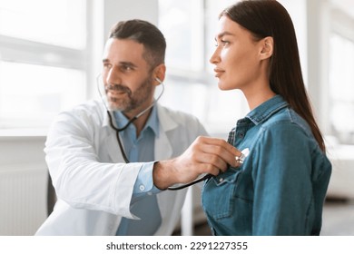 Caring male doctor using phonendoscope, examining young female patient heart rate at consultation in hospital. Man nurse or GP using stethoscope, listen to lady heartbeat in clinic - Powered by Shutterstock