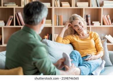 Caring Man Massaging Feet Toes Of His Wife While They Relaxing On Couch In Living Room, Happy Middle Aged Couple Resting Together In Cozy Home Interior, Enjoying Domestic Leisure, Selective Focus - Powered by Shutterstock