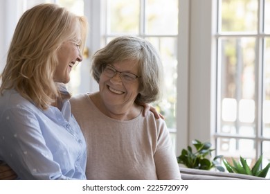 Caring middle-aged woman hugging her senior grey-haired mother in glasses standing together at home laughing enjoy positive friendly talk and time together. Multi-generational family, ties and love - Powered by Shutterstock