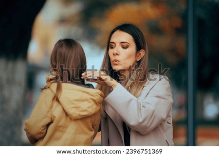 
Caring Mom Arranges the Jacket of her Daughter Outdoors. Loving perfectionist mother taking care of her kids appearance 
