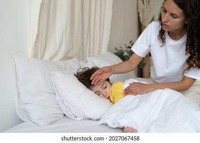 Caring Mom Check Small Sick Boy Temperature With Hand. Ill Kid With Flu Or Covid Illness Sleep In Bed Under Blanket With Concerned Mother On Bedside. Child Cure At Home And Parent Healthcare Concept