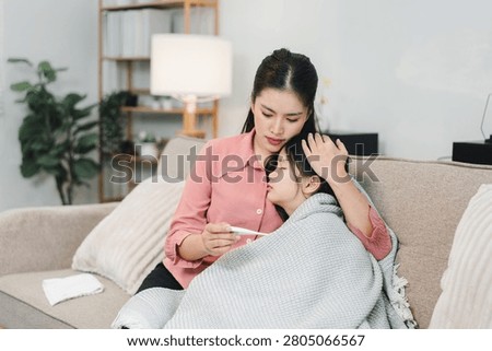 A caring mother checking her sick childs fever with a digital thermometer at home.