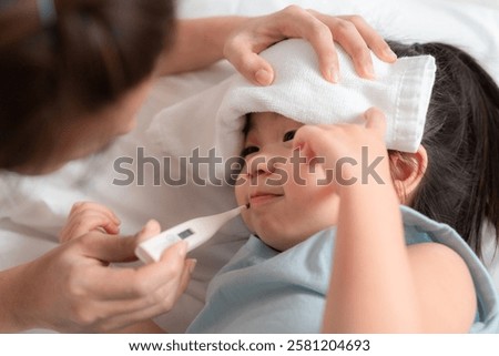 Caring Mother Checking Temperature of Sick Asian Child with Fever at Home in Comfortable Setting