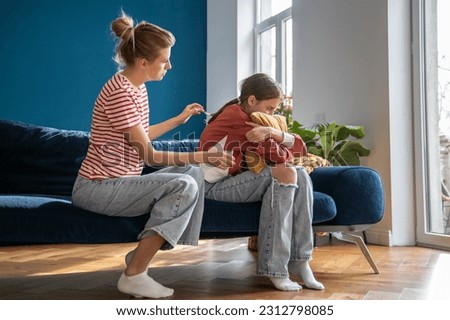 Caring mother cuddles teenage girl sitting on sofa and hug pillow. Concept mom care for child mental health. Parent support daughter problems in school. Communication problems between parent and kids
