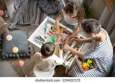 Caring Mother Playing Dinosaur Toys Sensory Sand Box Early Development With Boy And Girl Kids Top View. Family Enjoy Entertainment Education Fine Motor Skills Constructor Learning At Comfortable Home