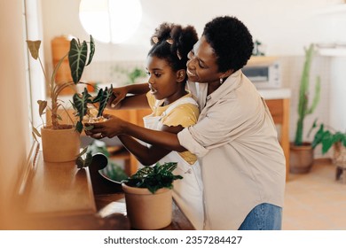 Caring mother shows her daughter how to water indoor plants with a spray bottle. Happy mom and daughter enjoying gardening and nurturing their potted plants together amidst beautiful flowers. - Powered by Shutterstock