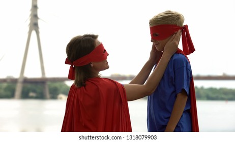 Caring Mother In Superhero Costume Looking With Love At Son, Proud Of Her Child