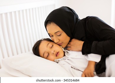 Caring Muslim Mother Kissing Baby Boy While He Is Asleep