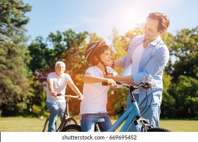 Caring Nice Dad Putting On A Helmet On His Son