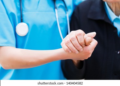 Caring Nurse Or Doctor Holding Elderly Lady's Hand With Care.