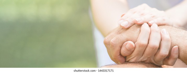 Caring nurse helping senior man sitting on bench in gaden. Asian woman, caucasian man. Holding hands, with copy space. Web banner frame.