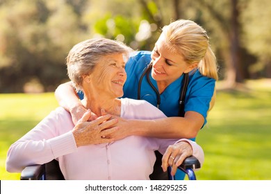 Caring Nurse With Senior Patient Outdoors