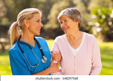 Caring Nurse Talking To Senior Woman Outdoors