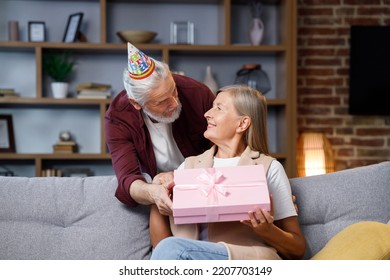 Caring Old Husband Giving Romantic Birthday Present To Excited Mature Wife, Loving Older Man Surprise Happy Middle Aged Woman, Open Pink Box, Kiss, Hug Husband, Celebrating Together.