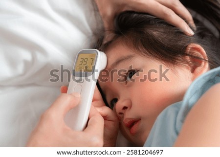 A caring parent checks the temperature of a young child using a digital thermometer at home, highlighting concern and the importance of monitoring health during illness.
