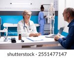 Caring senior doctor providing treatment options to male pensioner patient during clinical examination. Retired female physician giving medical advice to elderly man in hospital office.