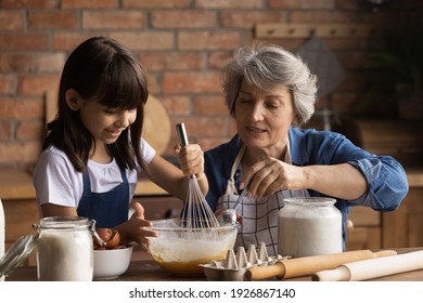 Caring Senior Hispanic Grandmother And Little 8d Granddaughter Have Fun Baking Cookies At Home Kitchen Together. Loving Elderly Latino Granny And Small Grandchild Cook Tasty Sweet Breakfast.