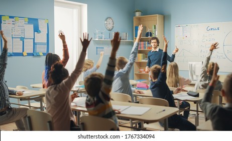 Caring Teacher Explains Lesson to a Classroom Full of Bright Diverse Children. In Elementary School with Group of Smart Multiethnic Kids Learning Science, Whole Classroom Raising Hands Knowing Answer