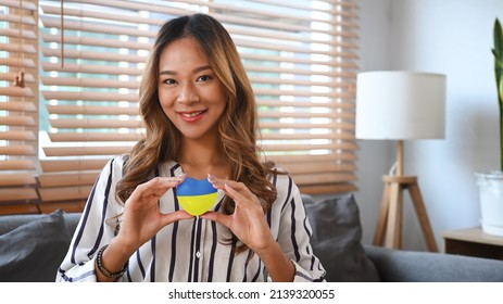 Caring woman holding heart with painted Ukraine flag. Concept of ending the war and pray for Ukraine. - Powered by Shutterstock