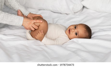 Caring Woman Making Gymnastics To Newborn Baby On Bed At Home, Unrecognizable Lady Helping Infant Kid To Relief Gas, Doing Exercises With Little Kid To Prevent Child Constipation, Moving Legs