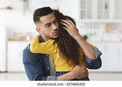 Caring Worry Arab Man Hugging Little Daughter, Comforting His Upset Child, Loving Middle Eastern Dad Embracing Small Girl At Home, Young Daddy Soothing Crying Depressed Kid, Closeup Shot