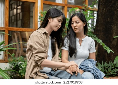 A caring young Asian woman is comforting and encouraging her sad friend as they have a serious conversation in a beautiful garden. friendship, togetherness, best friend - Powered by Shutterstock