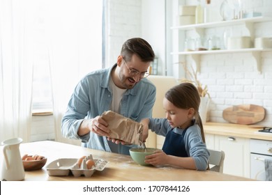 Caring Young Caucasian Father And Cute Little Preschooler Daughter Bake In Kitchen At Home Together, Happy Loving Dad Teach Small Girl Child Cooking, Preparing Pancakes Or Biscuits For Breakfast